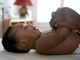 Parent holding a smiling baby's hands