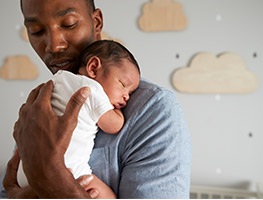 Dad holding a sleeping newborn baby on his shoulder