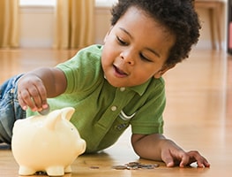 Toddler putting a coin in a piggy bank
