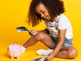 Toddler with a piggy bank holding money 