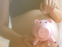 Pregnant woman putting a coin in a piggy bank